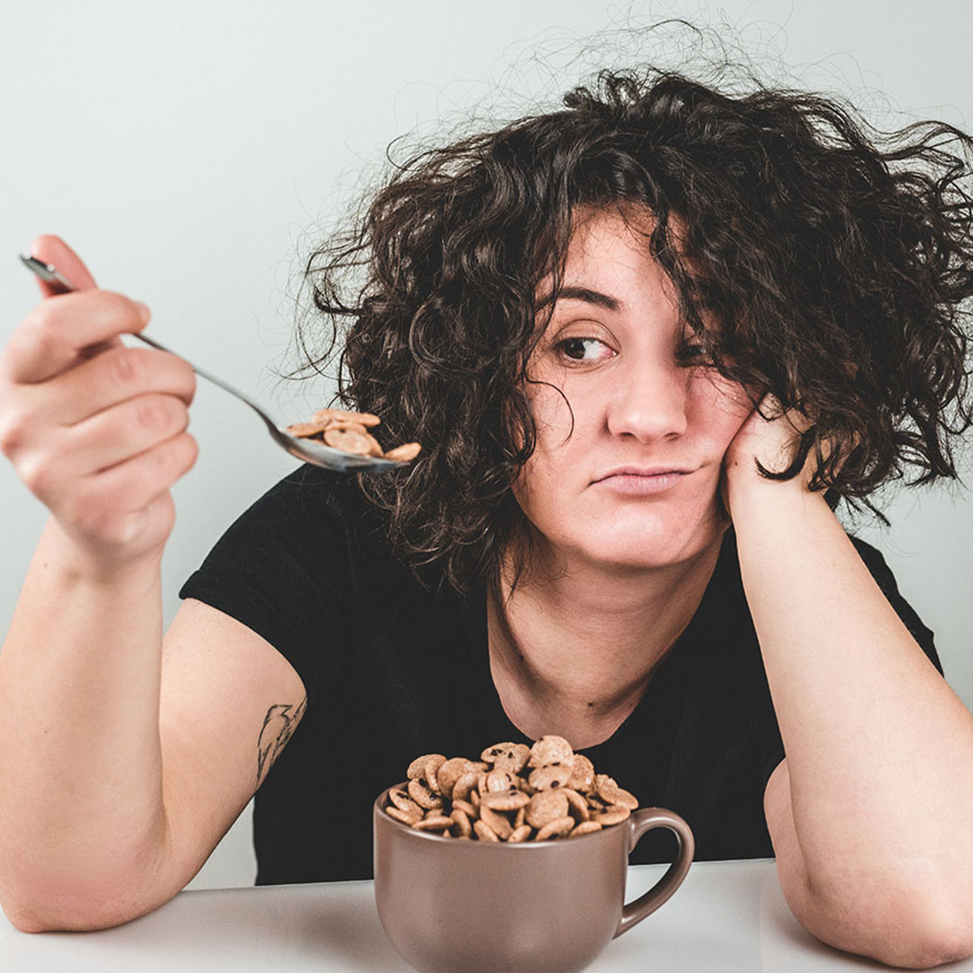 Image of woman looking at her spoon as she starts to shovel sugary cereal in her mouth