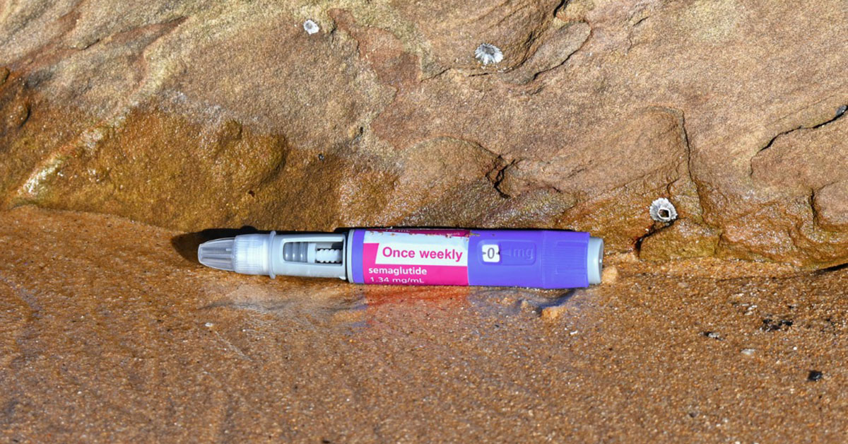 Semaglutide Injection discarded on sandy beach.